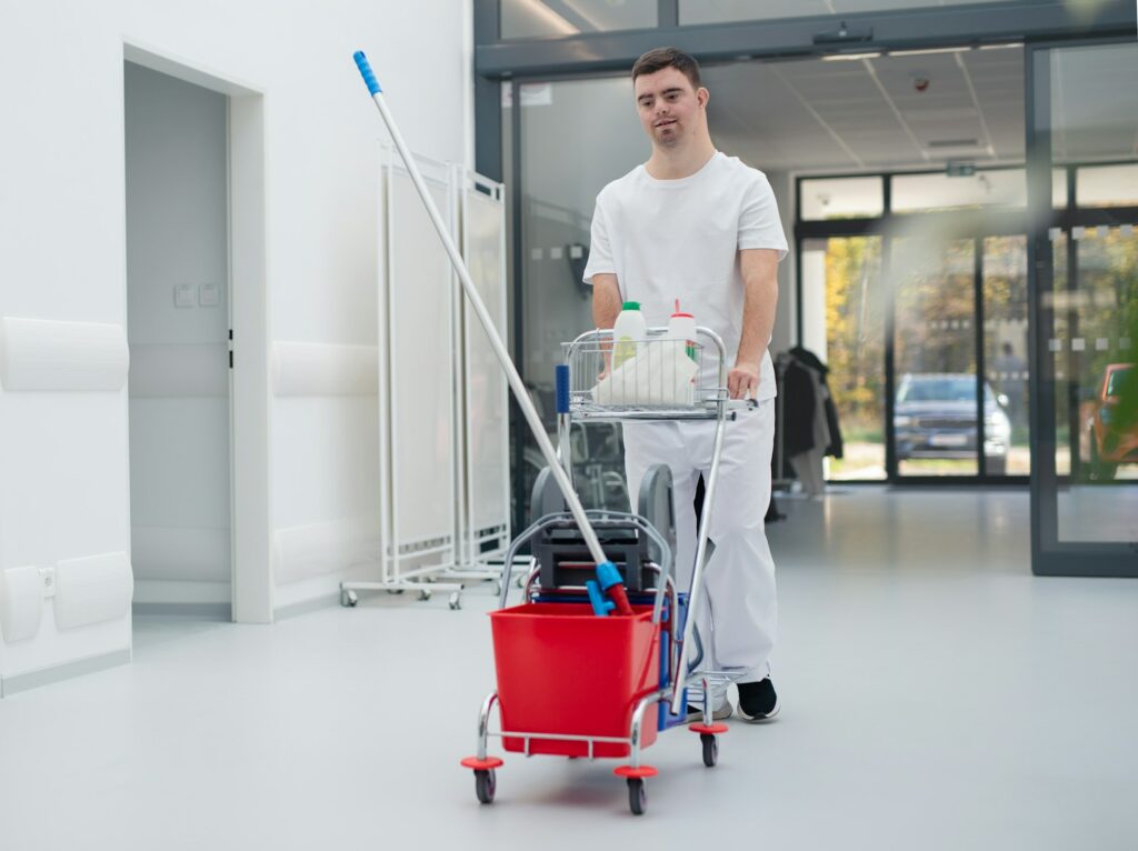 Young man with down syndrome working in a hospital as cleaner. Concpet of integration people with