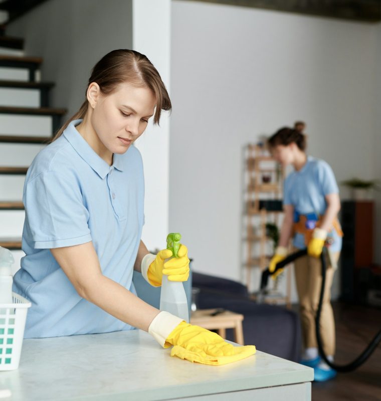 Cleaning service worker wiping dust from furniture